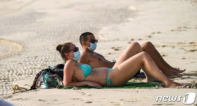 UAE 두바이 해변에서 코로나19 영향으로 커플이 마스크를 쓰고 일광욕을 즐기고 있다. © AFP=뉴스1 © News1 우동명 기자