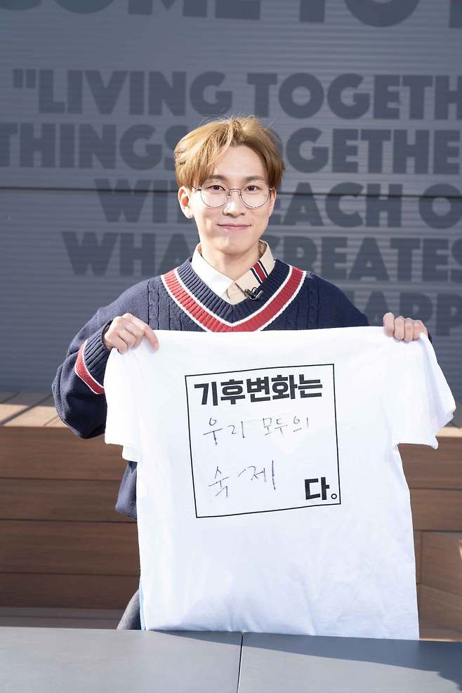 Seo Eun-kwang of BTB holds up a T-shirt that reads, “Climate change is everyone’s homework.” (Climate Media Hub)