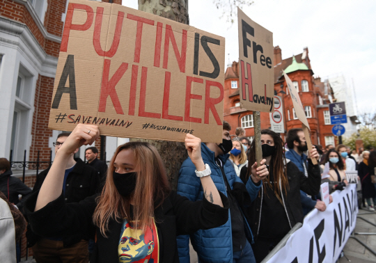 러시아에서 21일 야권 지도자 알렉세이 나발니의 석방을 요구하는 대규모 시위가 벌어진 가운데 시위대가 블라디미르 푸틴 대통령을 ‘살인자’라고 적은 팻말을 들고 있다.  EPA 연합뉴스