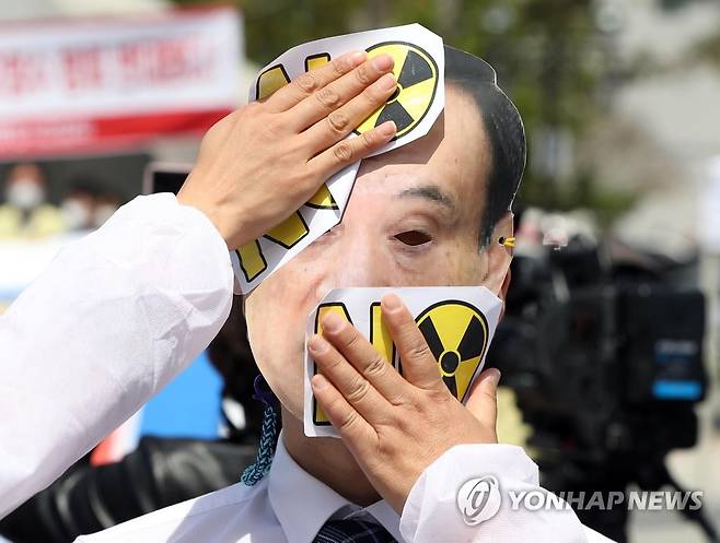일본 후쿠시마 원전 오염수 방류 반대 (통영=연합뉴스) 김동민 기자 = 환경단체 환경운동연합 회원이 26일 경남 통영시 정량동 이순신공원에서 열린 '후쿠시마 원전 오염수 방류 규탄 통영대회'에서 일본 스가 요시히데 총리 가면에 원전 반대를 알리는 스티커를 부착하고 있다. 2021.4.26 image@yna.co.kr