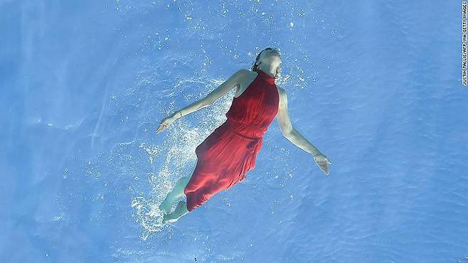 붉은색 드레스를 입은 한 여성 모델이 스카이 풀에서 수영하는 모습.(사진=AFP 연합뉴스)