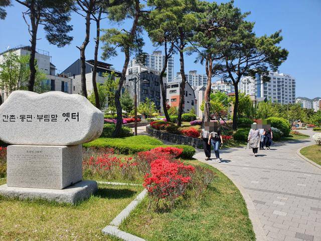 동편마을을 알리는 표지석 옆 산책로를 따라 시민들이 지나가고 있다.