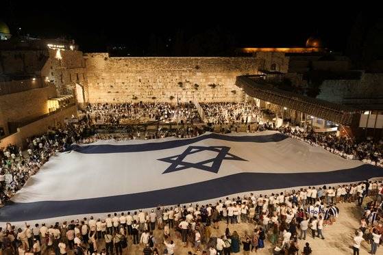 9일(현지시간) 예루살렘 올드시티 통곡의 벽에서 사람들이 거대한 이스라엘 국기를 들고 있다. 로이터