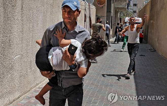 이스라엘군 공습에 아이 안고 대피하는 팔레스타인 남성 (가자시티 AFP=연합뉴스) 11일(현지시간) 팔레스타인 가자지구의 중심도시 가자시티에서 이스라엘군의 공습으로 한 남성이 아이를 품에 안은 채 대피하고 있다. 이슬람의 3대 성지 알아크사 사원 내에서 벌어진 팔레스타인 시위대와 이스라엘 경찰의 충돌 이후 이스라엘군과 가자지구를 통치하는 무장 정파 하마스의 무력 충돌이 이틀째 이어지고 있다. leekm@yna.co.kr