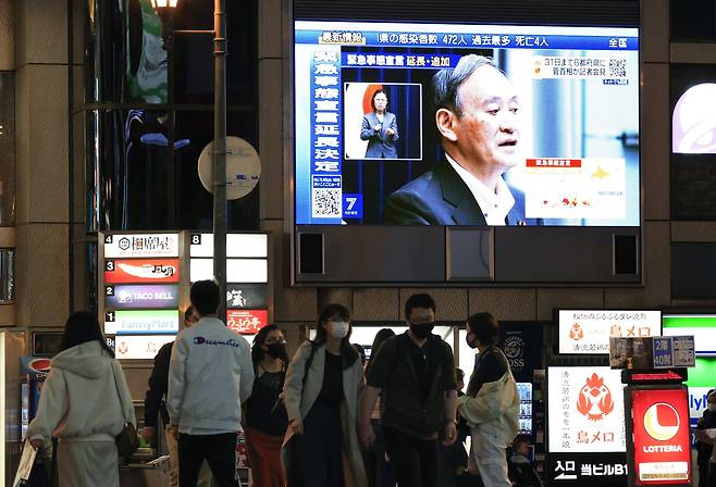 지난 7일 오후 스가 요시히데 일본 총리가 신종 코로나바이러스 감염증(코로나19) 긴급사태에 관한 기자회견을 하는 모습이 일본 오사카시 도심에 설치된 대형 스크린에 중계되고 있다. /연합뉴스