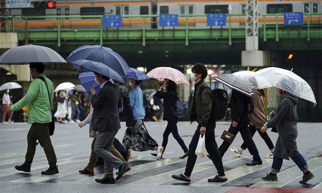 13일 일본 도쿄에서 코로나19 확산을 막기 위해 마스크를 쓴 시민들이 우산을 쓰고 건널목을 건너고 있다. 도쿄=AP뉴시