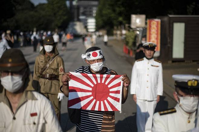 2020년 8월 15일 일본의 패전기념일 당시 욱일기를 든 남자가 도쿄 야스쿠니신사 앞을 걸어가고 있다.(사진=AFP제공)