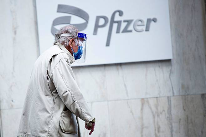 <YONHAP PHOTO-1049> (FILES) In this file photo taken on March 11, 2021, a man wearing facemask and shield walks past the Pfizer headquarters in New York one year after the pandemic was officially declared. - The Pfizer and Moderna Covid vaccines should remain highly effective against two coronavirus variants first identified in India, according to new research carried out by US scientists. The lab-based study was carried out by the NYU Grossman School of Medicine and NYU Langone Center and is considered preliminary because it has not yet been published in a peer-reviewed journal. "What we found is that the vaccine's antibodies are a little bit weaker against the variants, but not enough that we think it would have much of an effect on the protective ability of the vaccines," senior author Nathaniel "Ned" Landau told AFP on on May17, 2021. (Photo by Kena Betancur / AFP)/2021-05-18 05:12:13/ <저작권자 ⓒ 1980-2021 ㈜연합뉴스. 무단 전재 재배포 금지.>