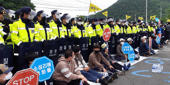 Police stand behind residents of Seongju County in North Gyeongsang on Tuesday as the residents attempt to block a road when the military deliver construction materials and daily necessaries to the Terminal High Altitude Area Defense (Thaad) base of the United States Forces Korea. [NEWS1]