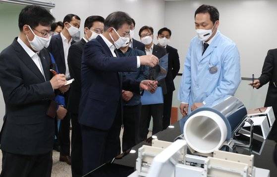 지난해 4월 문재인 대통령이 코오롱인더스트리 구미사업장 불화폴리이미드 공장을 찾아 코로나19 대응 현황 등에 대한 보고를 받고, 폴더블폰이나 폴더블노트북 화면에 붙이는 불화폴리이미드 필름을 살펴보고 있다. [청와대사진기자단]