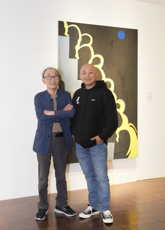 Artist Joo Jae-hwan, left, and webtoonist Joo Jae-Ho-min pose for photos after an interview with the Korea JoongAng Dailly in front of Joo Jae-hwan's painting ″Spring Rain Descending a Staircase″ (1980) at the ″Homin and Jaehwan″ exhibition held at the Seoul Museum of Art. [JEON TAE-GYU]