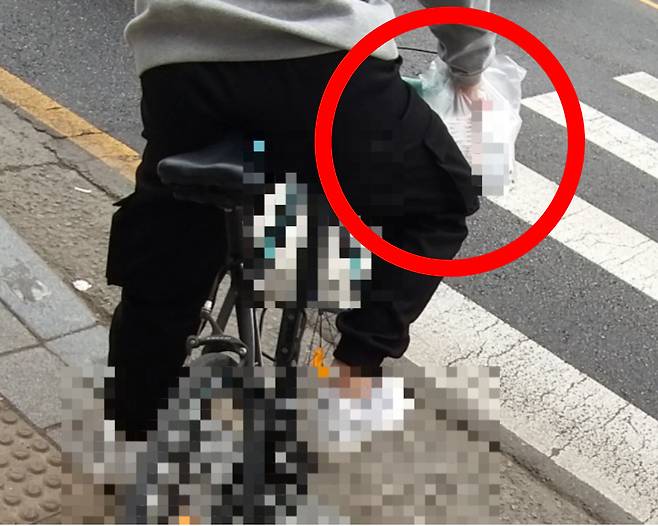 한 시민이 영수증이 붙어있는 음식 봉지를 배달가방 없이 자전거 손잡이에 걸어놓은 채 배달에 나서고 있다. [온라인 캡처]
