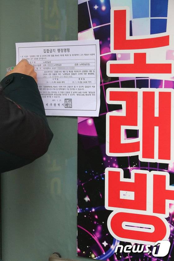 지난 1월 대구 노래연습장 도우미들의 신종 코로나바이러스 감염증(코로나19) 집단감염 발생으로 방역에 비상이 걸린 가운데 구청 관계자들이 관내 노래연습장에 집합금지 행정명령 안내문을 붙이고 있다. 뉴스1
