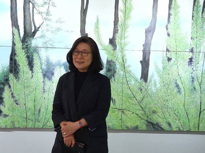 김보희 작가가 신작 ‘Towards’(2021)을 배경으로 작품을 설명하고 있다. 김 작가의 제주 작업실 바깥 정원 풍경을 화면에 담았다.