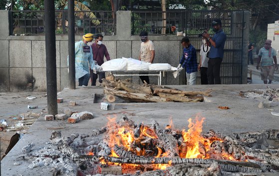 인도의 하루 코로나19 관련 사망자 수가 3000명대를 기록하던 지난달 12일 인도의 뉴델리에서 자원봉사자가 코로나19 사망자를 옮기고 있다. [EPA=연합뉴스]