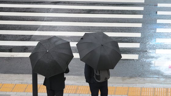 지난달 25일 오전 서울시 중구 태평로에서 시민들이 우산을 쓰고 출근하고 있다. 연합뉴스