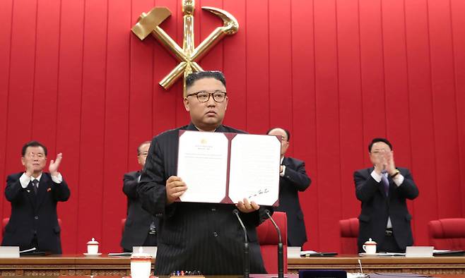 김정은 북한 국무위원장이 17일 열린 노동당 중앙위원회 제8기 제3차 전원회의에서 자신이 서명한 서류를 들어보이고 있다. 연합뉴스