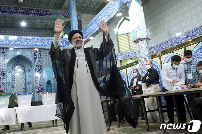 테헤란 시내의 한 투표소에서 18일 세예드 에브라힘 라이시 후보가 한 표를 행사한 뒤 손을 흔들어 보이고 있다. © 로이터=뉴스1