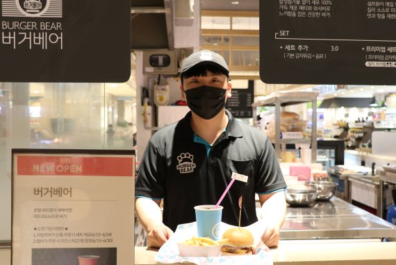 롯데백화점 대전점 지하 1층에 새로 오픈한 '버거베어' 매장에서 직원이 대표 매뉴인 레트로 버거베어 세트를 들어보이고 있다.