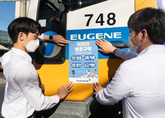 유진기업 부천공장 직원들이 어린이 교통안전 표어가 적힌 스티커를 레미콘 믹서트럭에 부착하고 있다. 유진기업 제공.