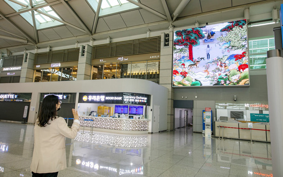 A visitor interfaces with an interactive media art installation at Incheon International Airport's Terminal 1 on Monday. The airport said the installation uses cutting-edge information and communications technology. [YONHAP]