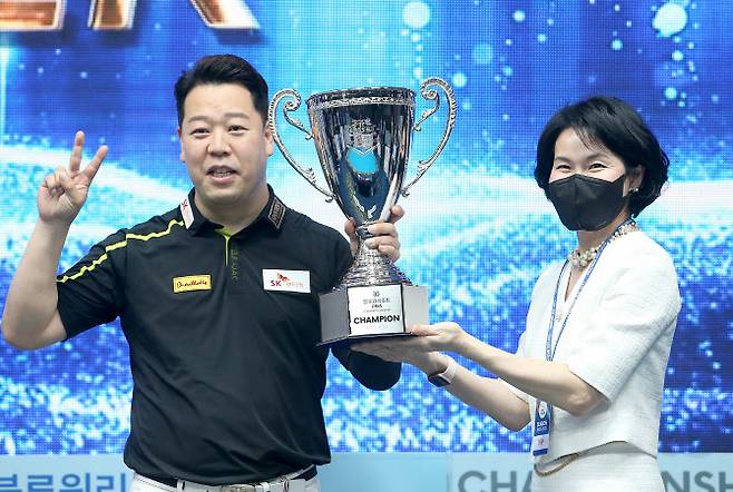 강동궁(왼쪽)(이 프로당구 PBA ‘블루원리조트 챔피언십’에서 우승한 뒤 윤재연 블루원리조트 대표로부터 트로피를 받고 있다. 사진=PBA 제공