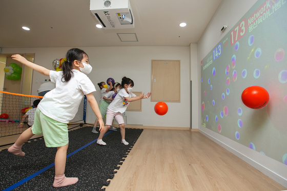 Children participate in an indoor field day at the Yongsan District Office in Seoul on Tuesday. KT said it is working with four institutions within Yongsan on a metaverse field trip using its KT Real Cube system. Without having to wear special equipment, children can take part in the online field trip, which uses motion sensors so they can play games with other kindergarten children via virtual reality and augmented reality systems. [KT]