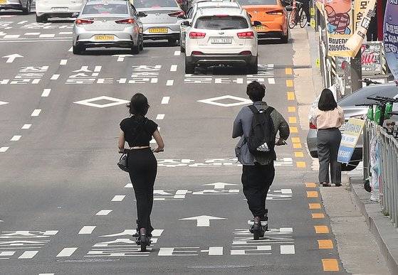 개인형 이동장치(PM) 운전자의 안전 강화를 위한 도로교통법 개정안이 시행된 6월13일 오후 서울 시내에서 한 커플이 헬멧을 미착용하고 도로를 달리고 있다. 우상조 기자