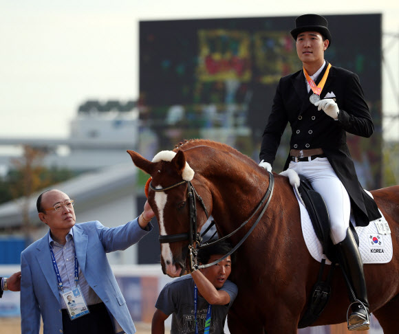 김승연(왼쪽) 한화그룹 회장이 2014 인천 아시안게임 승마 마장마술 개인전에서 은메달을 획득한 아들 김동선(오른쪽)의 말을 만져보고 있다. 연합뉴스