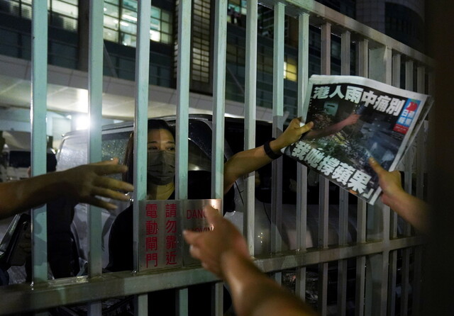 24일 홍콩 청콴오 지역에 자리한 <핑궈일보> 사옥으로 지지방문을 온 독자들에게 이 회사 직원이 갓 인쇄돼 나온 마지막 신문을 건네주고 있다. 홍콩/로이터 연합뉴스