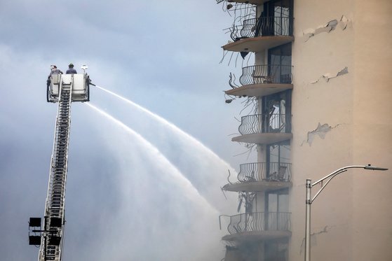 붕괴된 아파트를 향해 물을 뿌리는 소방대원들. AFP=연합뉴스