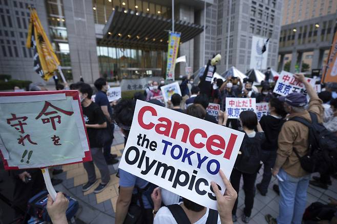 도쿄올림픽 개막이 한 달 앞으로 다가온 지난 23일 일본 도쿄도청 앞에서 시민들이 ‘도쿄올림픽 취소하라’고 적힌 피켓을 들고 시위를 벌이고 있다. 도쿄｜AP연합뉴스