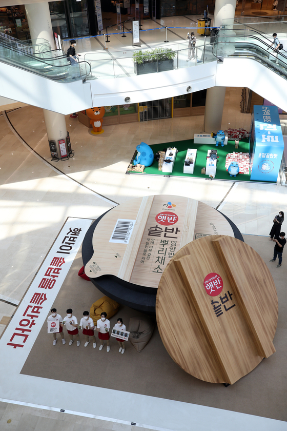 Models promote CJ CheilJedang's new instant rice product on Sunday before a mega-sized installation in the shape of a gamasot, a traditional pot used for rice cooking, at the Times Square in Yeongdeungpo, western Seoul. [YONHAP]
