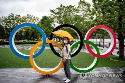 (도쿄 AFP=연합뉴스) 도쿄올림픽 개막식이 보름 앞으로 다가온 지난 8일 마스크를 쓴 한 여성이 도쿄 올림픽박물관 앞의 오륜 조형물 앞에서 포즈를 취하고 있다.