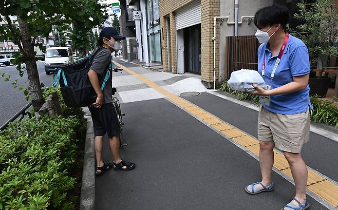 2020 도쿄올림픽 취재진이 14일 도쿄 분쿄구 미디어호텔 앞에서 음식 배달 서비스인 우버이츠를 이용해 식사를 배달받고 있다. 도쿄올림픽 조직위의 권고에 따라, 일본에 입국하는 외국 취재진은 3일간 호텔 내에서 자가격리를 해야 한다. 이날 일본 스포츠 전문지인 닛칸스포츠는 조직위가 공식 개장한 선수촌에서 음식 배달을 허용했다고 보도했다. 도쿄=허정호 선임기자