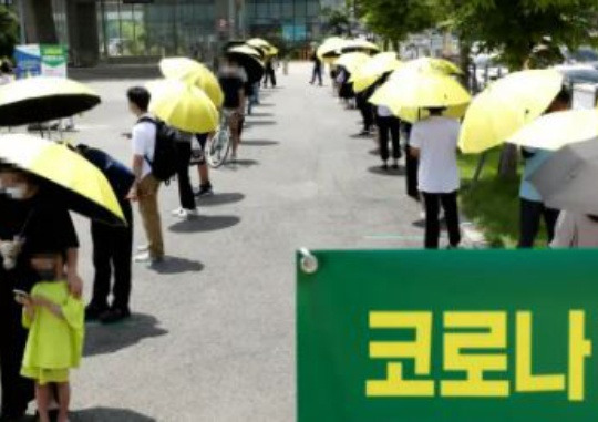 On the afternoon of July 14, when new cases of COVID-19 reached a record high, citizens try to evade the heat with parasols provided by Seocho-gu while waiting to get tested in front of the temporary screening clinic set up in the square in front of the Express Bus Terminal in Seocho-gu, Seoul. Kim Ki-nam