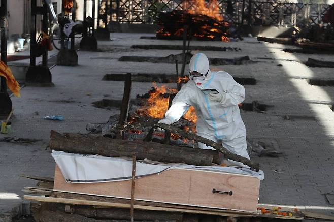 지난 4월23일(현지시간) 인도 카슈미르주 잠무의 화장터에서 코로나19로 숨진 사람의 장례식이 진행되는가운데 방호복을 입은 가족이 마지막 인사를 하고 있다. /AP=뉴시스