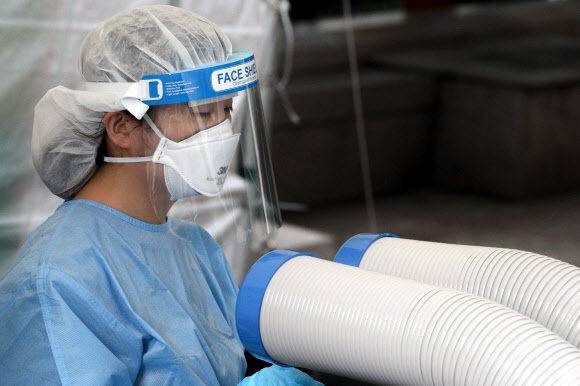 전국 대부분 지역에 폭염특보가 내려진 15일 서울 종로구민회관 임시선별검사소에서 의료진이 냉풍기 바람을 쐬며 더위를 식히고 있다. 뉴스1