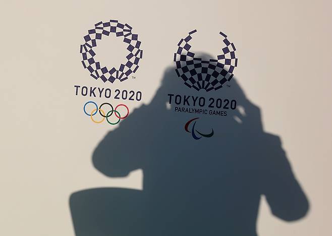 2020 도쿄올림픽 개막을 나흘 앞둔 가운데, 개막도 하기 전부터 1년 연기와 무관중 개최로 천문학적인 액수의 경제적 손실이 예상된다는 전망이 나오고 있다. 지난 17일(현지시간) 하시모토 세이코(橋本聖子) 도쿄올림픽 및 패럴림픽 조직위원회 회장의 그림자가 도쿄올림픽·패럴림픽 로고 위에 드리운 모습. [로이터]