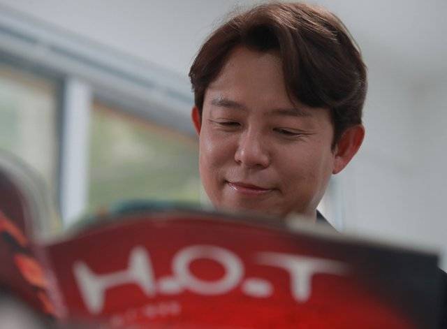 H.O.T. 화보집 속 자신의 옛 모습을 보며 미소짓고 있는 토니안.