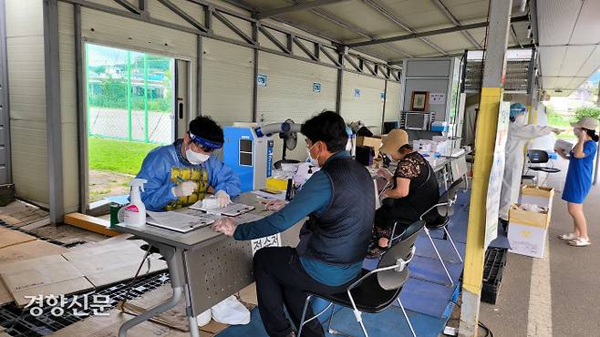 충북 청주시 상당보건소에 마련된 선별진료소에서 지난 19일 오후 접수업무를 맡고 있는 강신규씨(왼쪽)가 방호복 위에 노란색 아이스조끼를 입고 서류를 작성하고 있다. 이삭 기자 isak84@kyunghyang.com