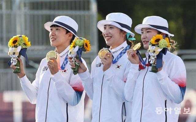 25일 압도적인 실력을 과시하며 올림픽 양궁 단체전 9연패를 달성한 한국 여자 양궁 대표팀의 안산, 장민희, 강채영(왼쪽부터)이 금메달과 꽃다발을 들어 보이며 활짝 웃고 있다. 이번이 첫 올림픽 출전이었던 세 선수는 8강에서 결승까지 세 경기 동안 단 한 세트도 내주지 않는 완벽한 경기를 펼쳤다. 도쿄=홍진환 기자 jean@donga.com