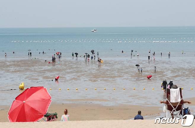 지난 25일 인천광역시 중구 을왕리해수욕장에 임시폐장을 알리는 플래카드 뒤로 피서객들이 물놀이를 즐기거나 모래사장에서 휴식을 취하고 있다 /사진=뉴스1
