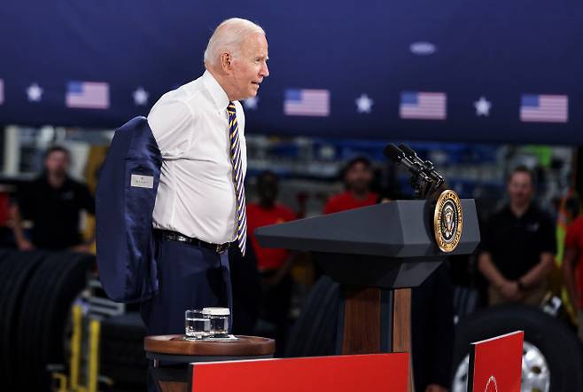 조 바이든 미국 대통령이 28일(현지시간) 펜실베이니아주 매컨지의 맥 트럭 공장을 방문해 연설을 하기 전 양복 웃옷을 벗고 있다. 매컨지|로이터연합뉴스