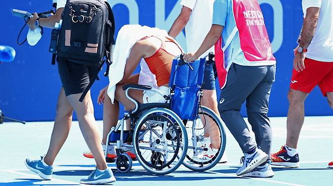 지난 28일 일본 도쿄의 아리아케 테니스 파크에서 열린 도쿄올림픽 테니스 여자 단식 8강전에서 마르케타 본드로우쇼바(42위·체코)를 상대로 경기를 펼치던 파울라 바도사(29위·스페인)가 무더위에 지쳐 기권한 뒤 휠체어를 타고 경기장을 나서고 있다. 로이터=연합뉴스