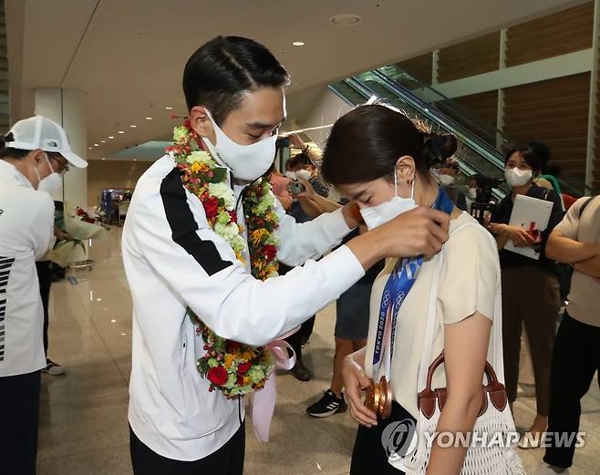 아내에게 메달 걸어주는 김정환 (영종도=연합뉴스) 임화영 기자 = 2020 도쿄올림픽 펜싱 사브르 남자 단체전에서 금메달, 개인전에서 동메달을 거머쥔 대한민국 국가대표팀 김정환 선수가 29일 오후 인천국제공항 제2여객터미널을 통해 귀국, 아내의 목에 메달 두개를 걸어주고 있다. 2021.7.29 hwayoung7@yna.co.kr