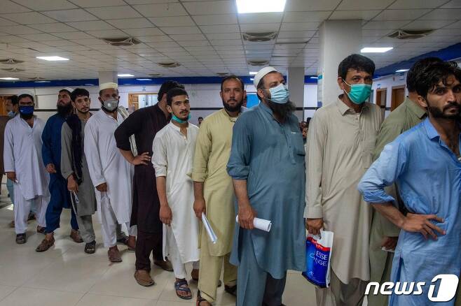 6일(현지시간) 파키스탄 페샤와르에 있는 코로나19 백신 접종 센터에서 중동 지역으로 갈 해외 근로자들이 모더나 백신을 맞기 위해 줄을 서 있다. © AFP=뉴스1 © News1 우동명 기자