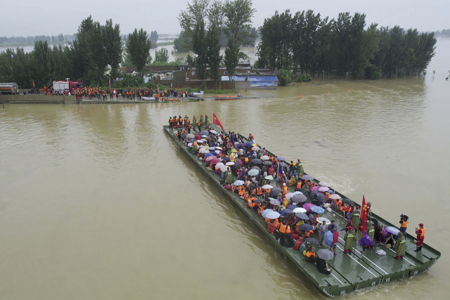 사상 최악의 폭우가 쏟아졌던 23일 중국 허난성 신샹에서 임시 보트를 이용해 고립된 수재민들을 실어 나르고 있다. /AP연합뉴스