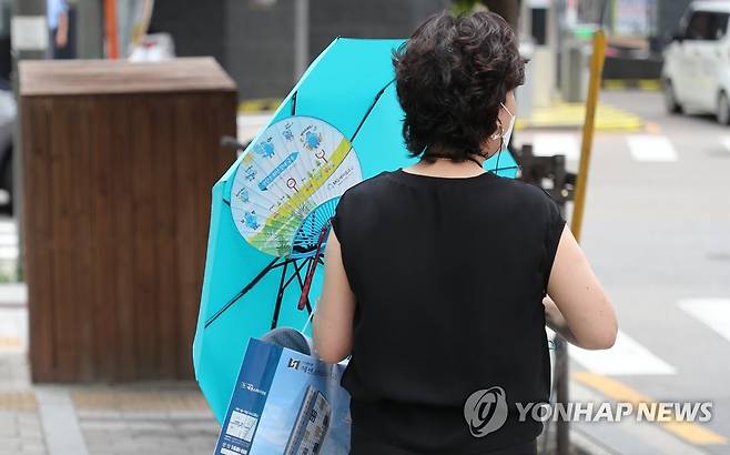 전국 흐리지만 한낮 35도…부채와 우산이 필요한 날씨 서울에 폭염 경보가 내려진 지난 19일 오후 서울 시내에 소나기가 내리자 우산을 쓴 시민이 발걸음을 재촉하고 있다. [연합뉴스 자료사진]