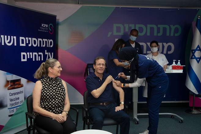아이작 헤르조그(60. 중앙) 이스라엘 대통령이 30일(현지시간) 서부 도시 라마트간의 한 병원에서 부인 미갈(왼쪽) 여사가 지켜보는 가운데 신종 코로나바이러스 감염증(코로나19) 3차 백신(부스터 샷)을 맞고 있다. /AP 연합뉴스
